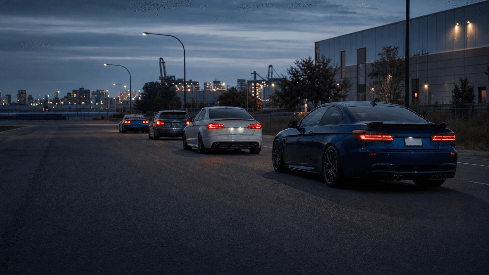 Four enthusiast cars beginning a coordinated convoy at blue hour